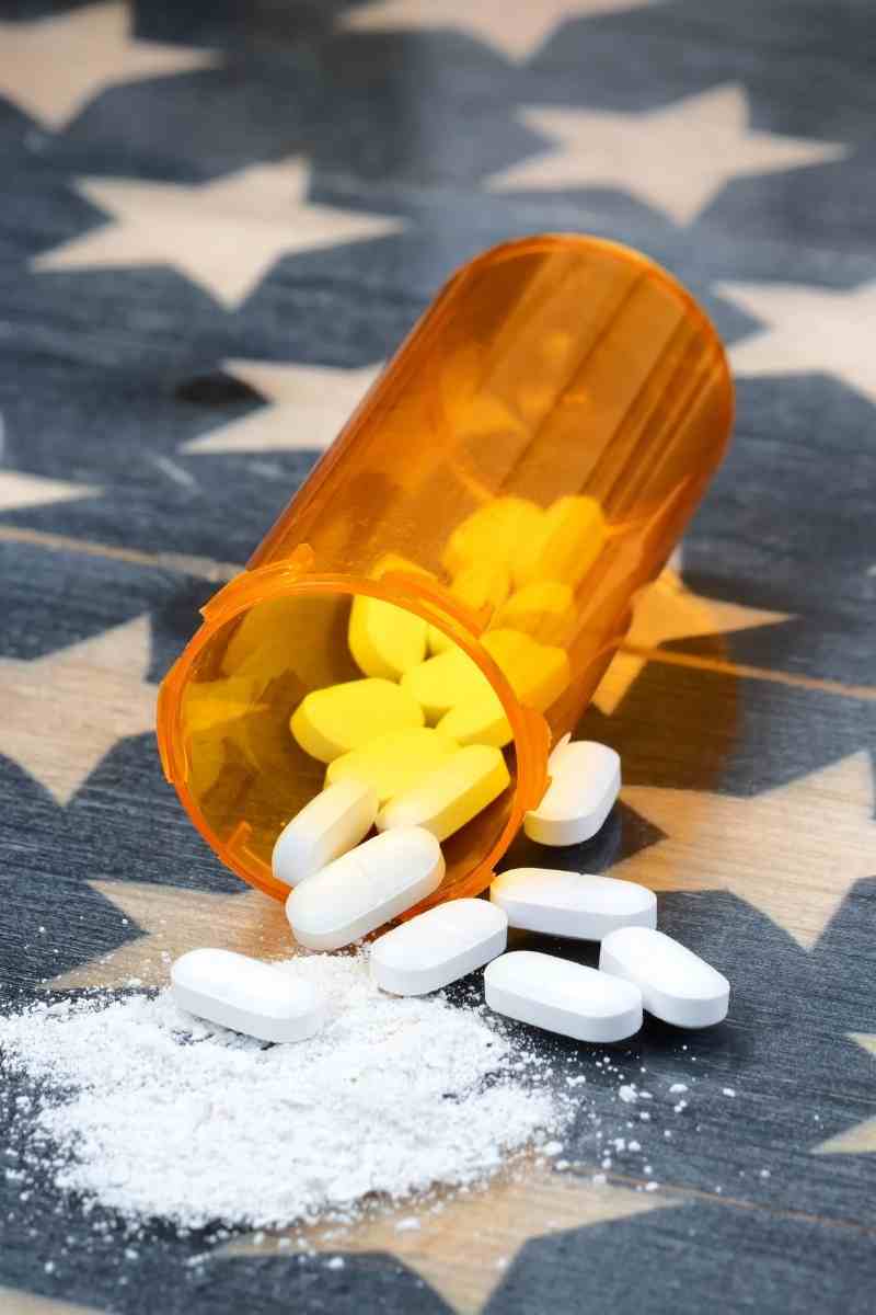 Orange prescription bottle with white and yellow pills spilled onto a surface